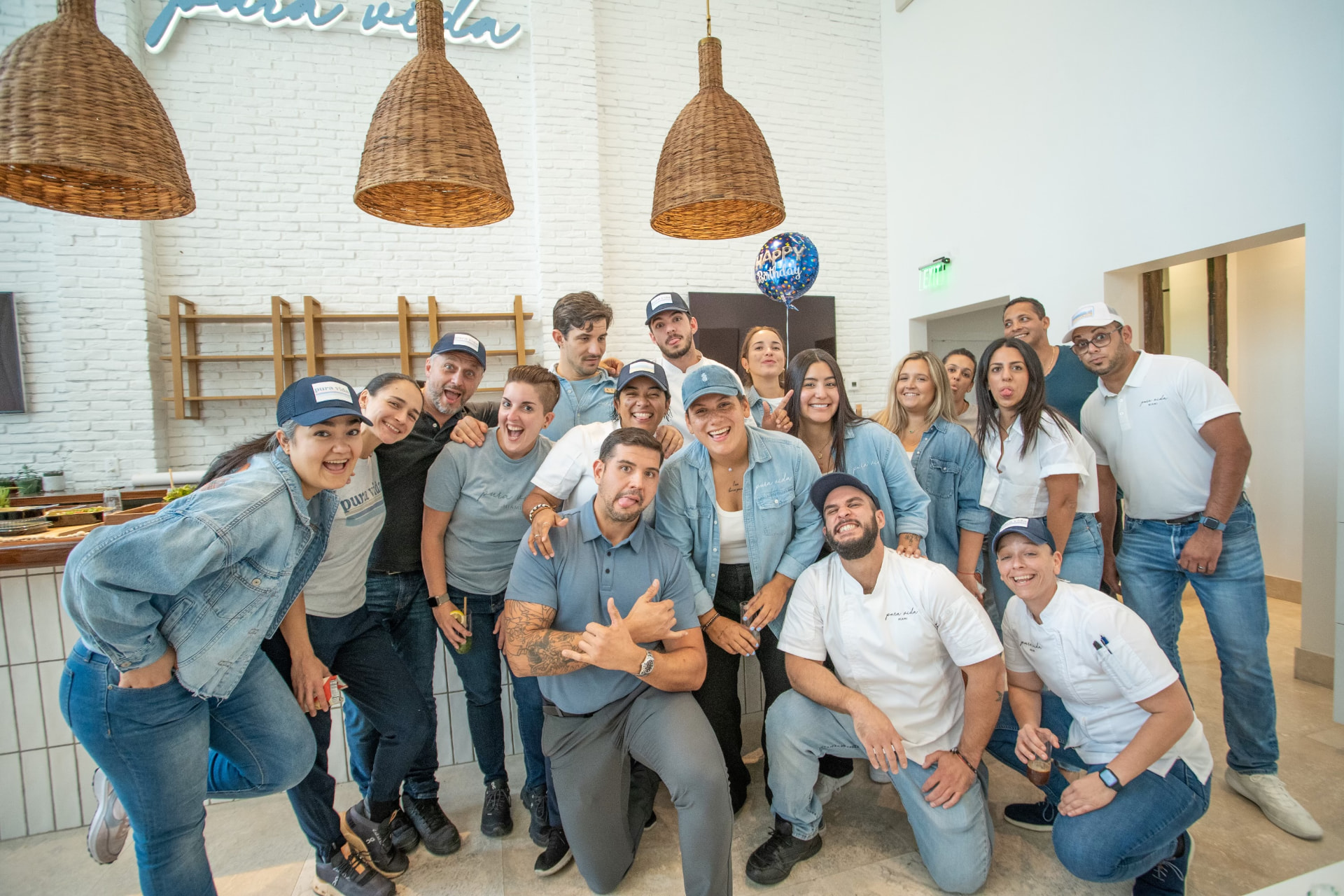 Large café team posing together under the Pura Vida sign