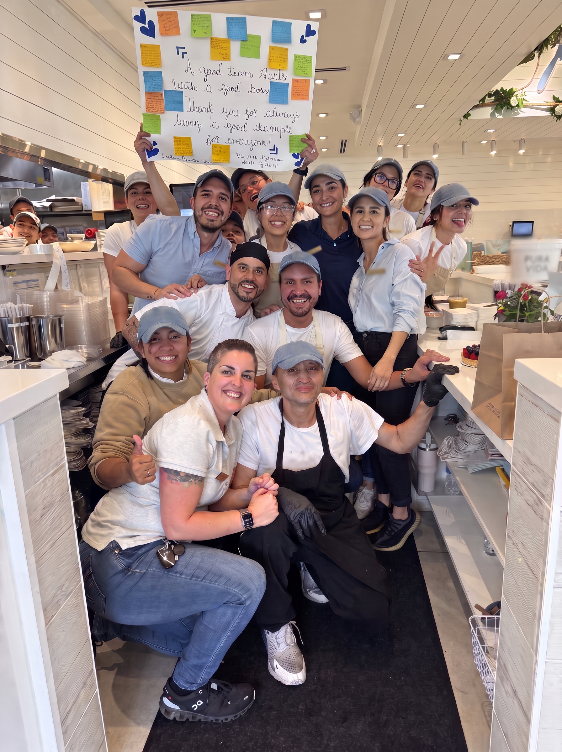 Team holding a handmade thank-you sign reading 'A good team starts with a good boss'